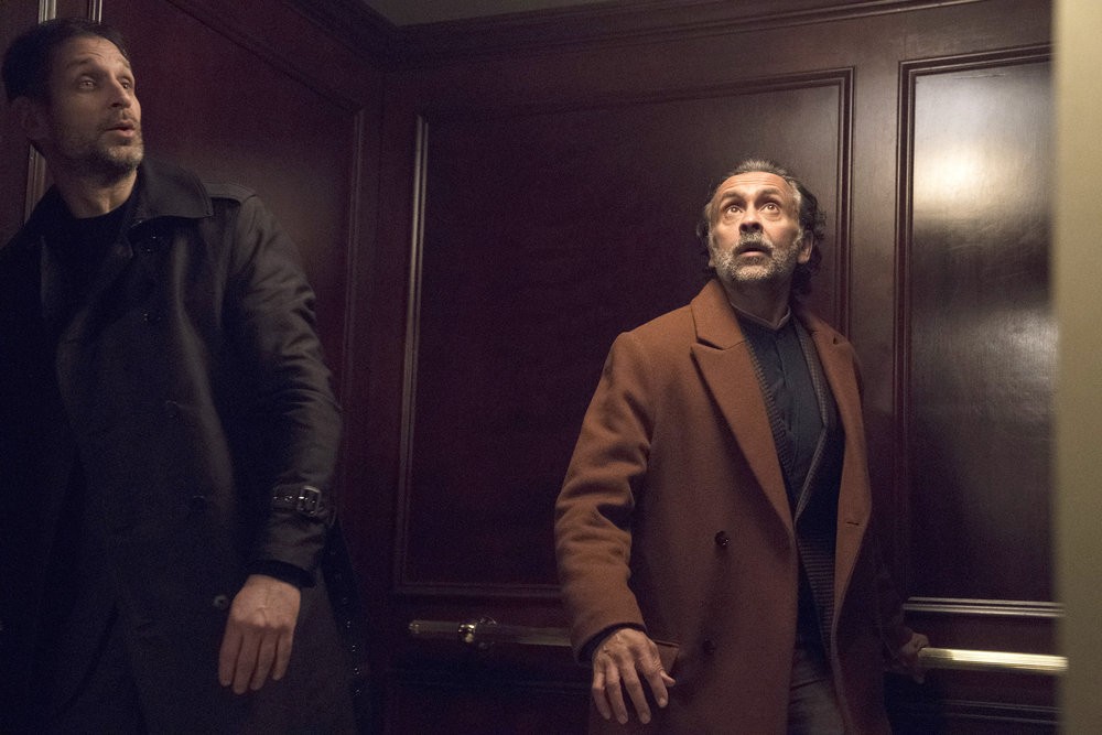 Un garde (Mustafa Gatollari ) et Zarak Mosadek (Bernard White) pris au piège dans l'ascenseur 