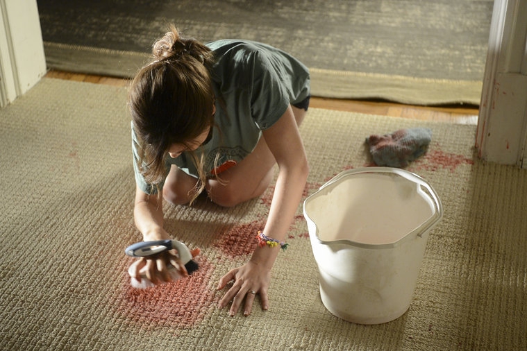 Elizabeth Keen nettoie une tâche sur le sol 