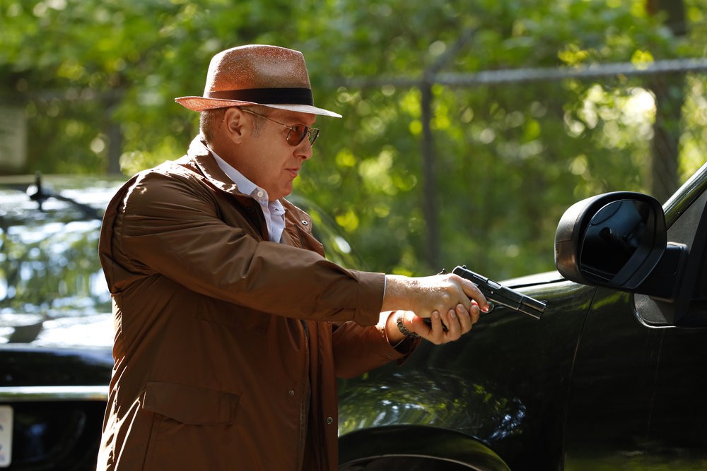 Raymond Reddington (James Spader), arme à la main, menace l'occupant d'une voiture