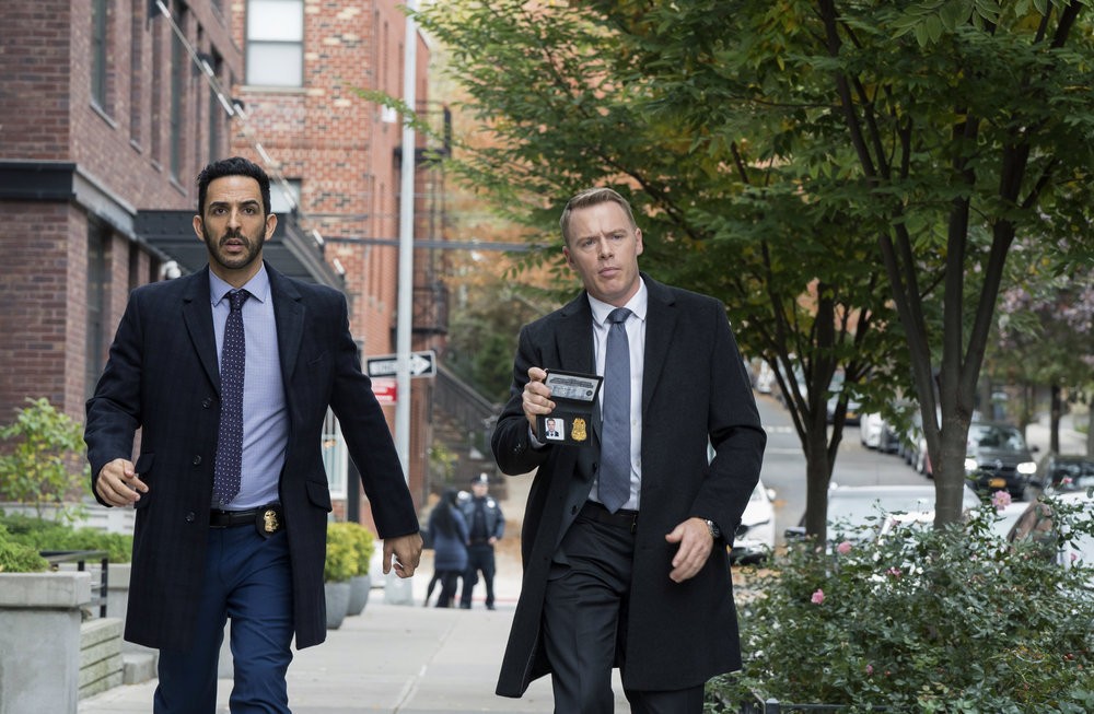 L'agent Donald Ressler (Diego Klattenhoff), qui montre sa plaque du FBI, arrive avec son collègue Aram Mojtabai (Amir Arison)  