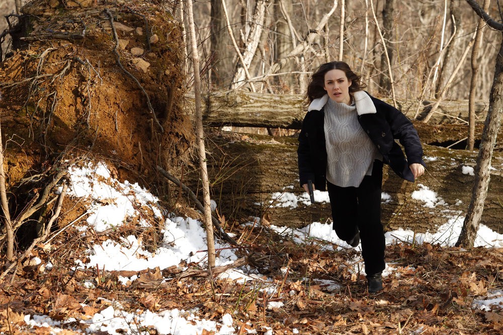 L'agent Elisabeth Keen (Megan Boone) court dans la forêt arme au poing