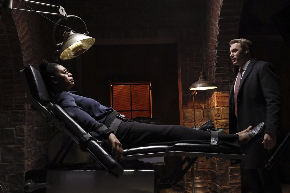 Lorsque l'agent Ressler (Diego Klattenhoff) arrive, Dr Laken Perillos (Laverne Cox) l'attend  attachée à sa propre chaise de torture