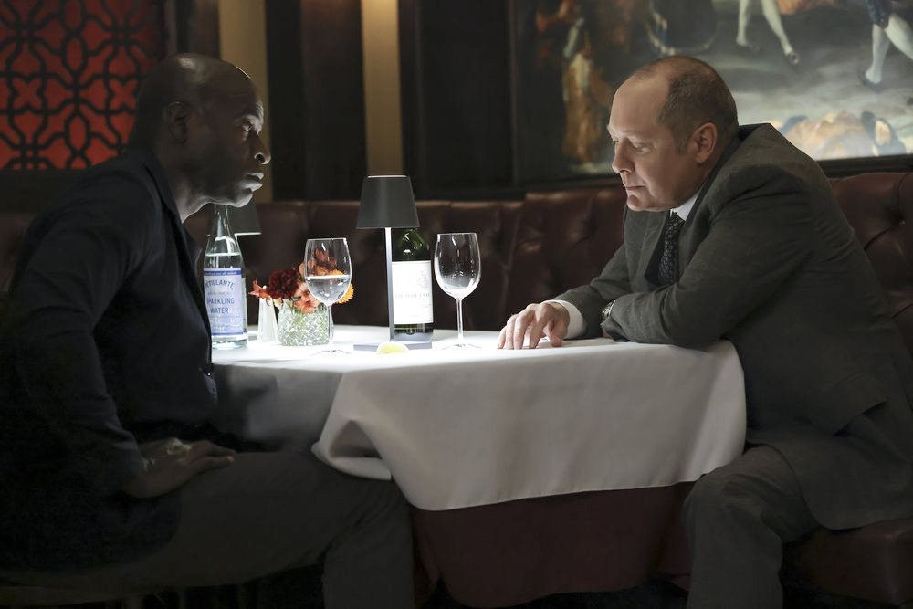 Dembe et Raymond discutent, assis à une table de restaurant
