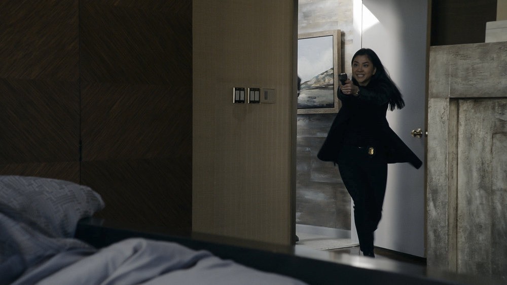 L'agent Park (Laura Sohn), menaçante, arme au poing