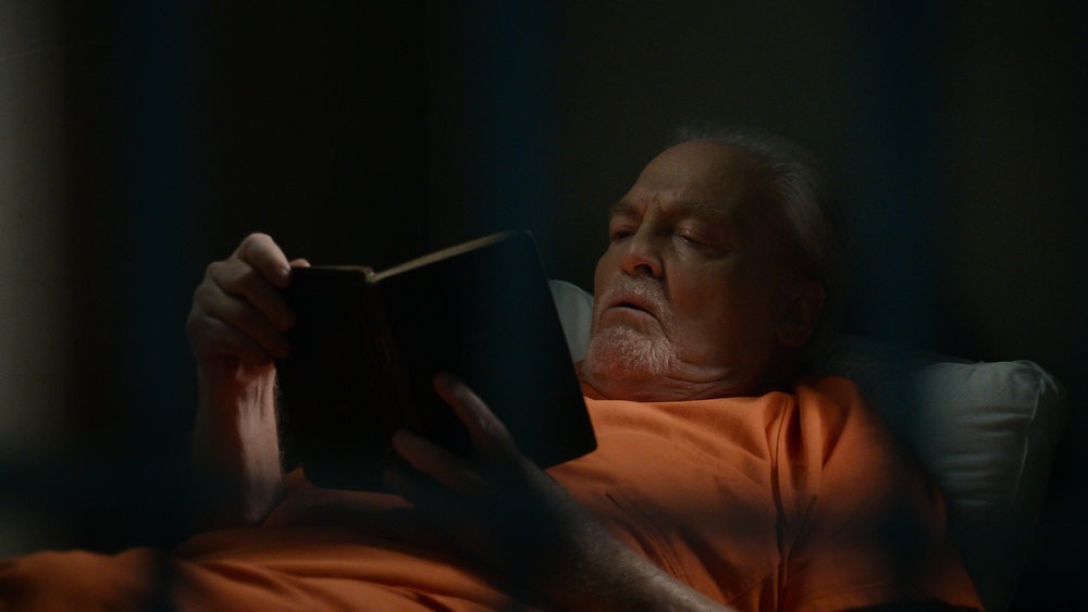 Robert Vesco (Stacy Keach) lit un livre en cellule