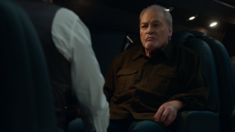 Robert Vesco (Stacy Keach) assis dans le jet de Reddington