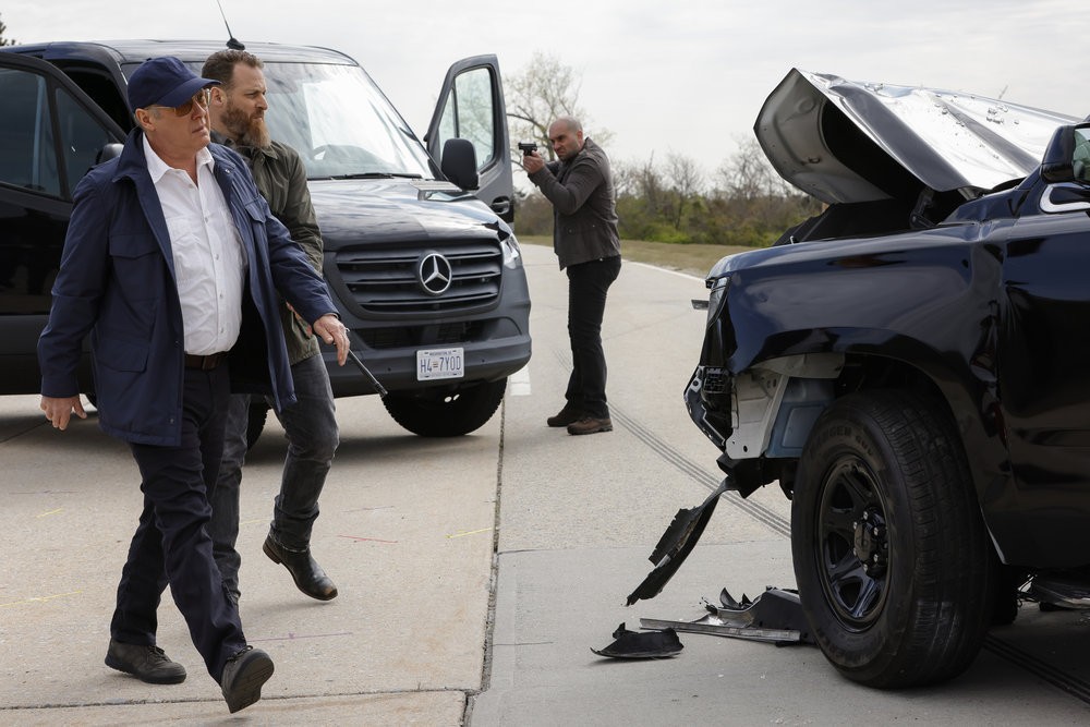 Raymond Reddington (James Spader) et Chuck (Jonathan Holtzman) se dirigent vers une voiture accidentée tandis qu'un homme de main assure leurs arrières