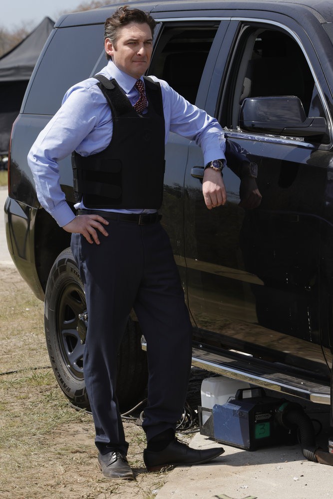 Toby Leonard Moore interprète le membre du congrès Arthur Hudson ici debout à côté d'un véhicule