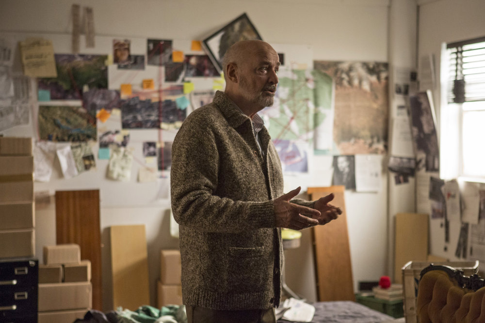 Howard Hargrave (Terry O'Quinn) dans son appartement rempli de preuves qu'il a amassé